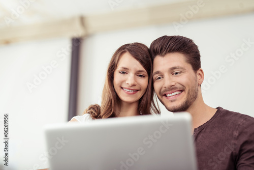 junges paar schaut gemeinsam auf laptop