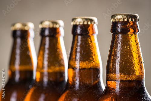 Freshly brewed beer bottles in a row over the grey concrete wall