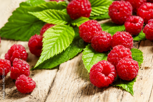 Fresh ripe raspberries with large leaves on the old wooden table
