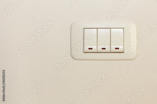 Fotografie Threefold multiply light switch on white wall.