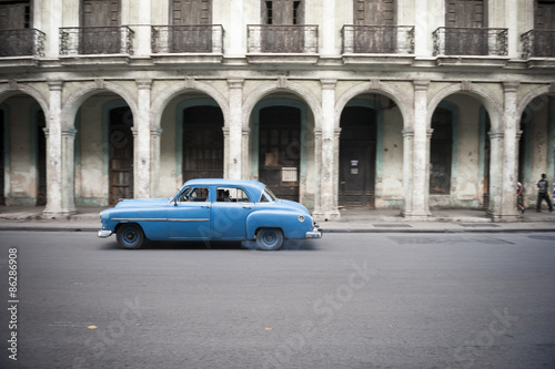 Old American car drives in front of the traditional architecture of a colonial arcade