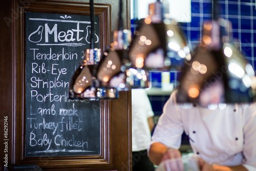 Chalk board menu in a restaurant/Chalk board menu in a restaurant on the background of the kitchen and the chef