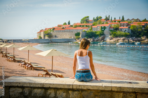 Beautiful young woman looking at the seascape and island Sveti Stefan. Montenegro, Europe. © oleg_p_100