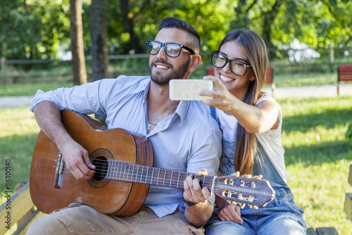 young couple in love takes a selfie while plays guitar