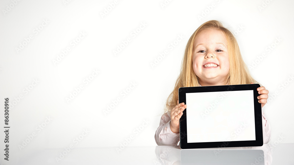 Cute little and smiling girl plays with a tablet Cute little and smiling girl plays with a tablet