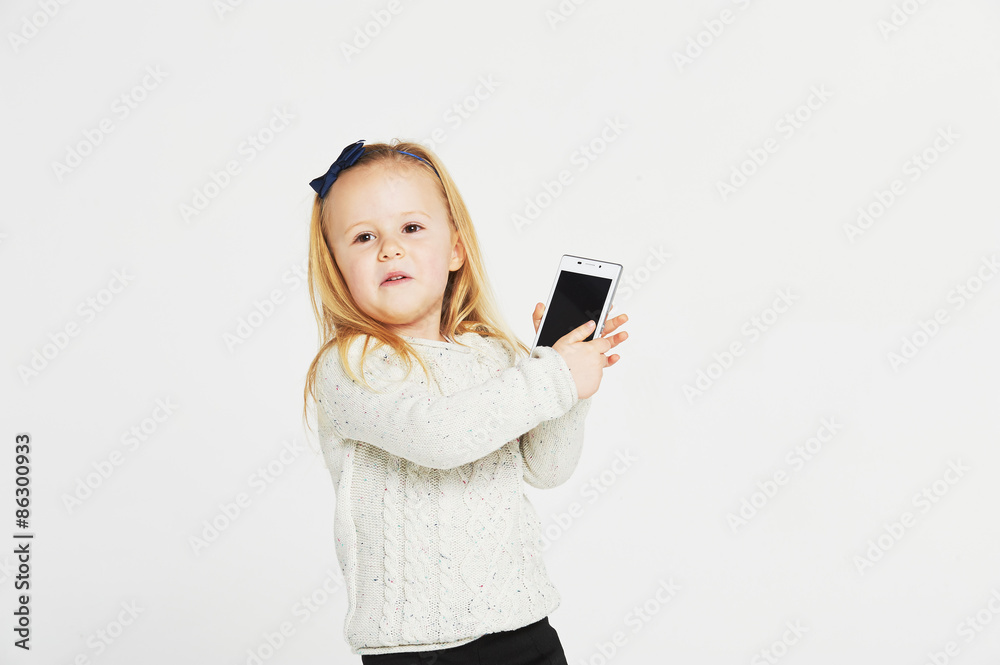 Cute little girl smiling and uses a smartphone, phone. Cute little girl smiling and uses a smartphone, phone.