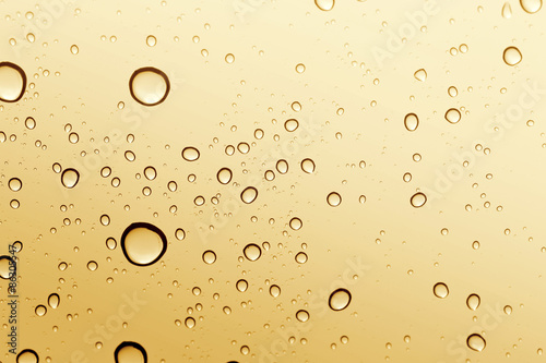 Gold water drop on glass mirror background.
