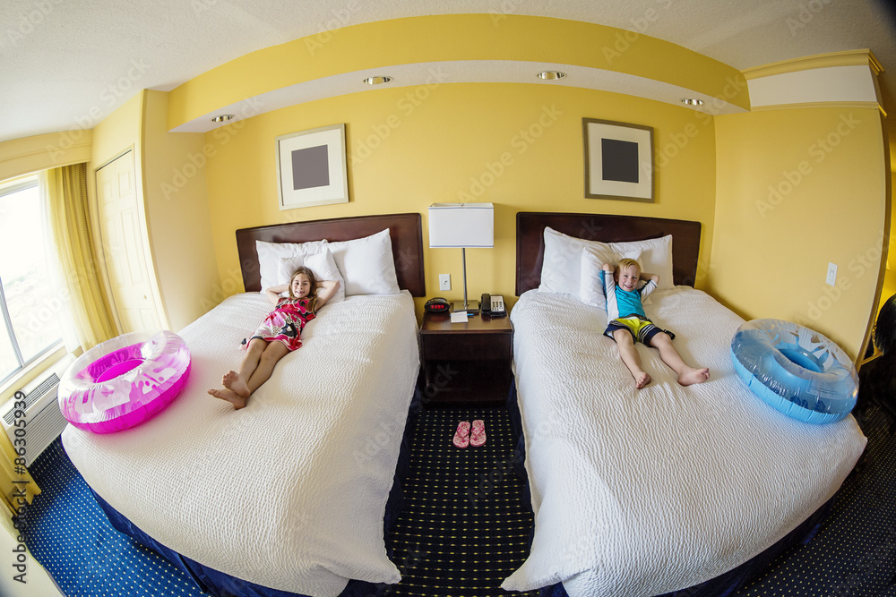 Cute kids laying on a bed in a hotel room while on fun family vacation