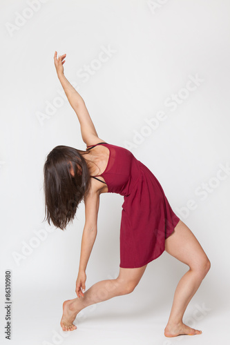 Sexy brunette woman dancing in red dress. Studio shot. White background