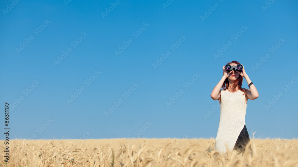 Naklejka premium girl with binocular at wheat field.