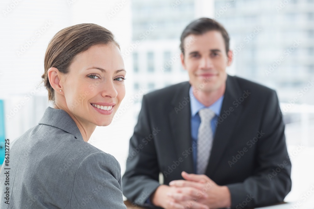 Smiling businessman and businesswoman looking at camera