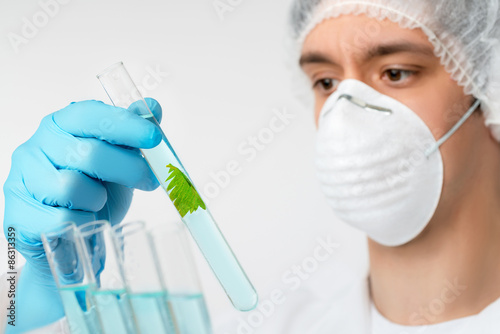 Scientist with brown eyes in protective wear with plant sample photo