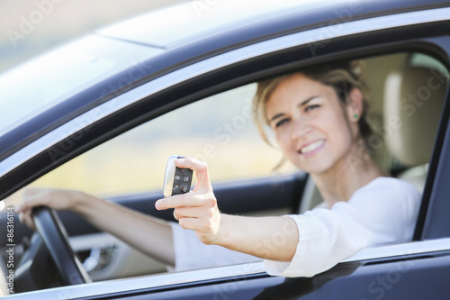Woman showing new car keys and car. Smiling