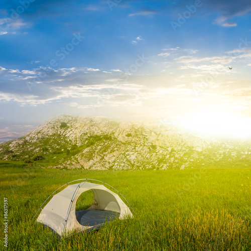 white touristic tent in a green hills at the sunrise