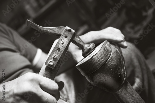 old artisian shoemaker hit shoes with hammer photo