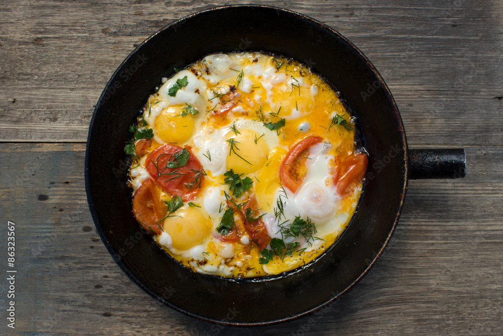 Fried eggs in a pan with vegetables.