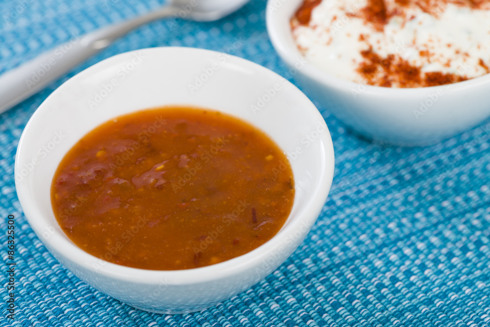 Chilli Dip - Hot chilli sauce in a white bowl on a a blue background.
Chilli Dip - Hot chilli sauce in a white bowl on a a blue background.