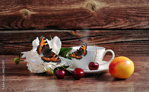 Coffee, cherry, flower and butterfly on a wooden background