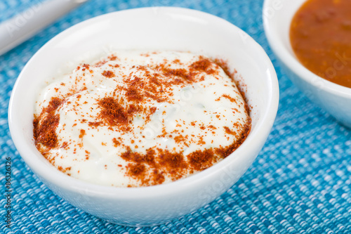 Paprika & Chive Dip - Sour cream and chive dip dusted with smoked paprika on a blue background. 