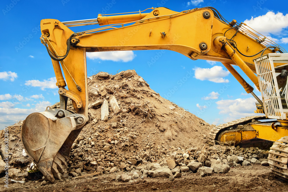 Excavator and heap of dirt in front of blue sky Excavator and heap of dirt in front of blue sky