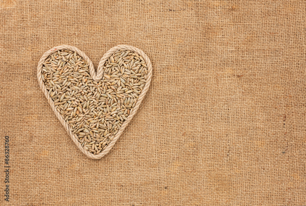 Heart made from rope with rye grains  lying on sackcloth