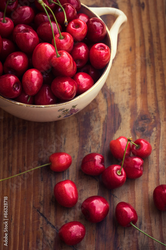 Ripe organic homegrown cherries in a vintage ceramic bowl, on wooden background