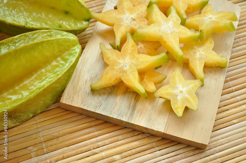 Top shot of starfruit and its slices on a wooden chopping board
