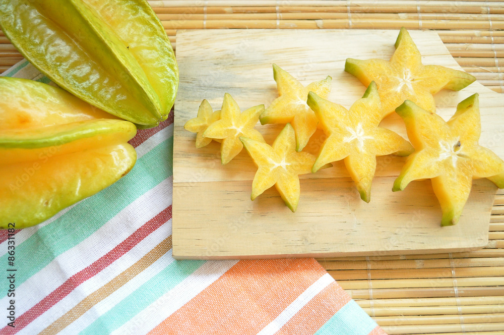 Top shot of starfruit on a wooden chopping board and stripe napkins
Top shot of starfruit on a wooden chopping board and stripe napkins