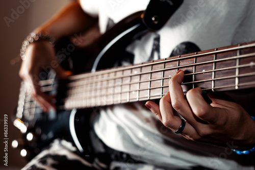 Young adult girl playing five string bass guitar. Color image in horizontal orientation