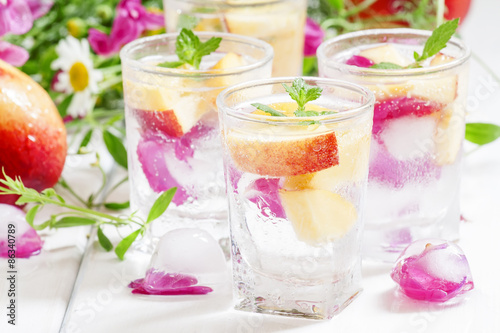 Fresh sparkling beverage with peaches and ice with rose petals o