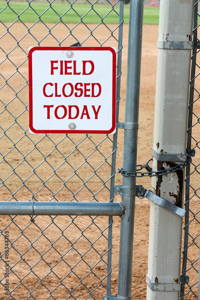 Field closed today sign on the gate to a softball field that is closed and locked Field closed today sign on the gate to a softball field that is closed and locked