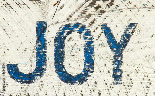 Wood sign with the word JOY painted on it.