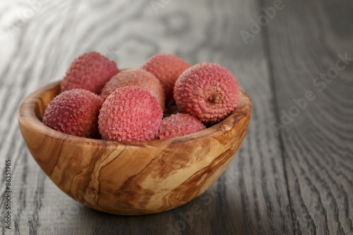 ripe lychees in wood bowl on table