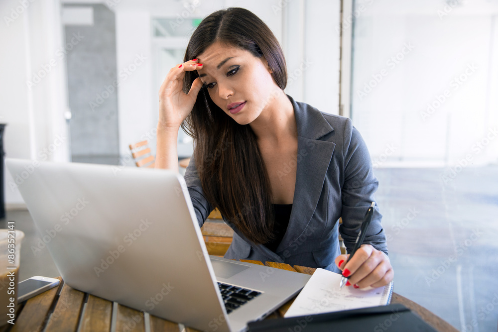 Beautiful Business woman student at a coffee shop working on a laptop cramming for exam midterm paperwork Beautiful Business woman student at a coffee shop working on a laptop cramming for exam midterm paperwork