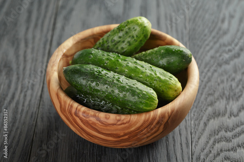 whole cucumbers in olive dowl on wood table