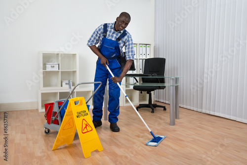 Janitor Cleaning Floor With Wet Floor Sign