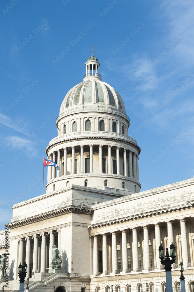 The classic architecture of El Capitolio building, inspired by the Pantheon in Paris and partly constructed in the United States, stands under bright Caribbean blue sky in Central Havana