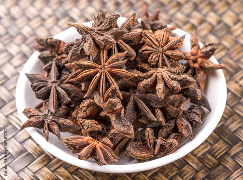 Star anise spice in white bowl over wicker background