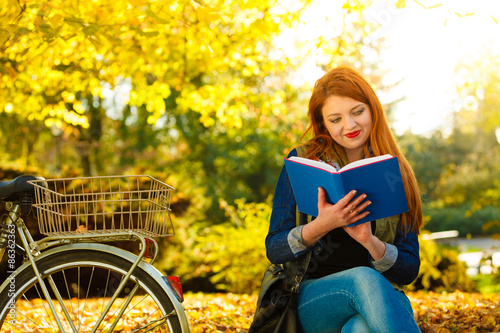 woman girl relaxing in autumnal park reading book