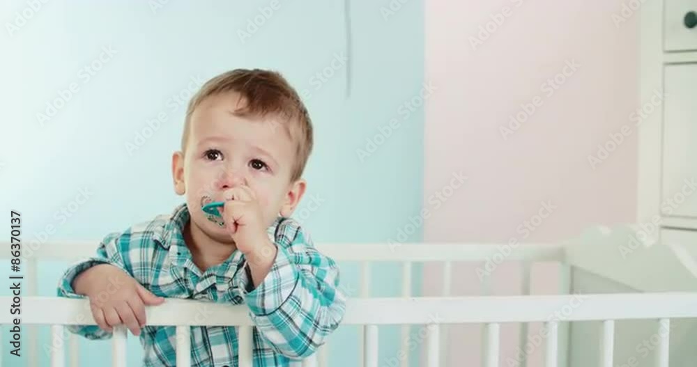 Little toddler in pyjamas crying and standing in his baby bed. Shoot on Digital Cinema Camera in 4K - ProRes 422 codec. Little toddler in pyjamas crying and standing in his baby bed. Shoot on Digital Cinema Camera in 4K - ProRes 422 codec.