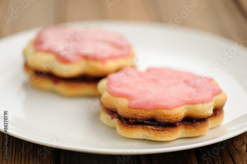 Two round double sand cakes decorated with pink icing and jam on
