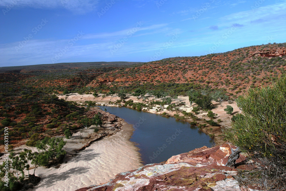 View down the red earthed and bush lined Gorge at Kalbarri NP under blue sky in Western Australia