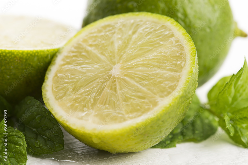 Green limes with mint and water drops on white background Green limes with mint and water drops on white background