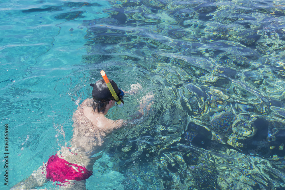Young man swims with mask for diving near coral
