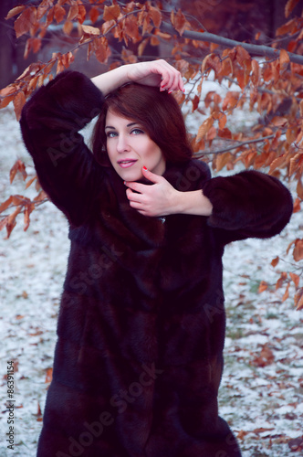 Outdoor portrait of beautiful smiling redheaded woman in fur coat