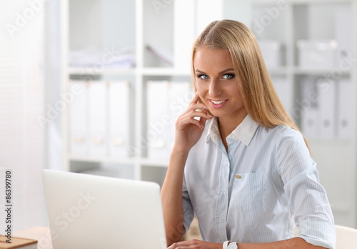Attractive businesswoman sitting on a desk with laptop in the