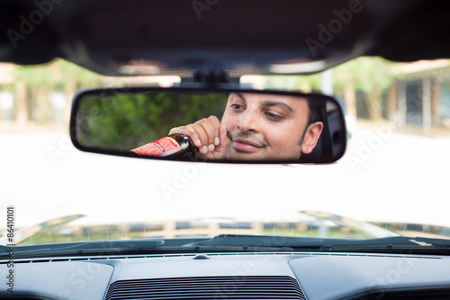 Closeup portrait, young guy drinking alcoholic beverage stoned, under the influence, isolated interior car windshield background. A menace driver to the road 