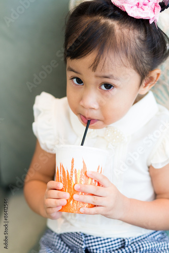 Adorable little girl drinking juice with paper cup
