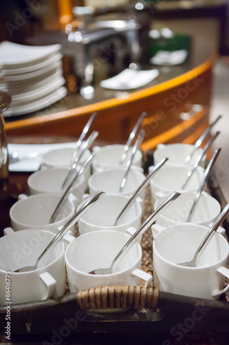 rows of pure white cup and saucer with teaspoon, reflection on t photo