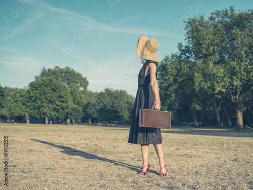Elegant young woman with briefcase standing in park © LoloStock